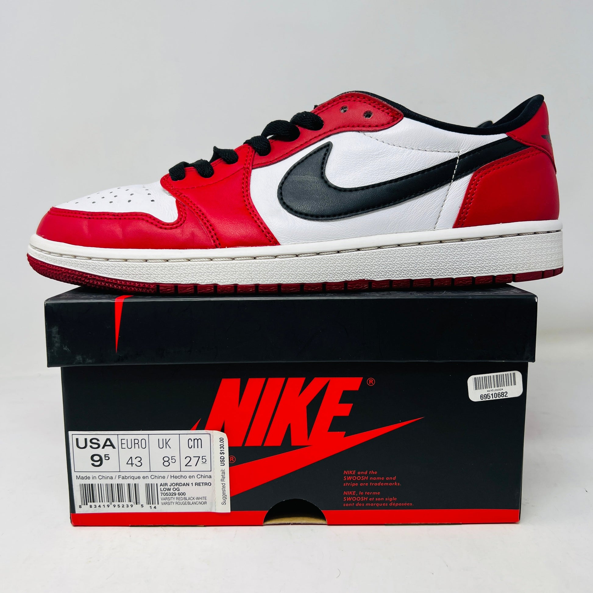 The Jordan 1 Retro Low Chicago (2016) sneaker, in red, white, and black with a bold black swoosh, sits stylishly on a sleek black shoebox marked with sizing for various regions.