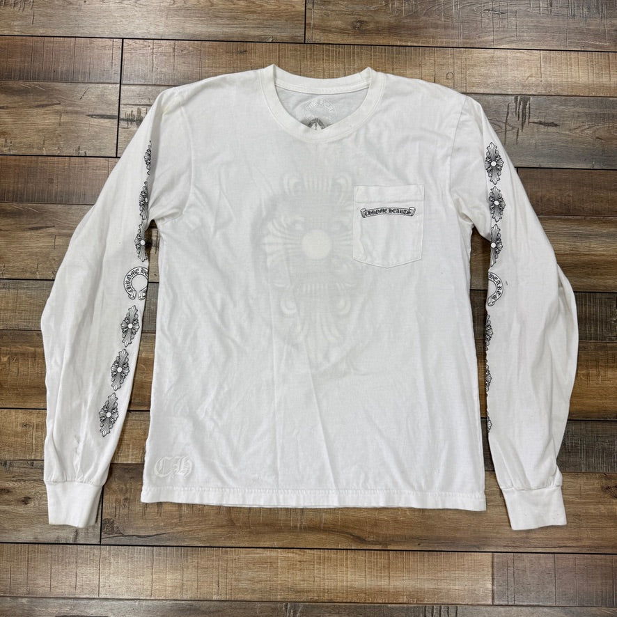 An authentic preowned Chrome Hearts Floral Cross L/S T-shirt in white, featuring a decorative sleeve pattern and a small chest pocket, set against a rustic wooden floor.