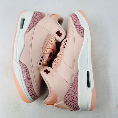 The BRAND NEW Jordan 3 Retro Valentines Day Treat Yourself (2025) (Womens) by Jordan, in pink and cream with textured heel and toe patterns, sits on a closed red shoebox. It features a translucent sole, red eyelets, and an authentic pendant on the laces sparkling like GEMS.