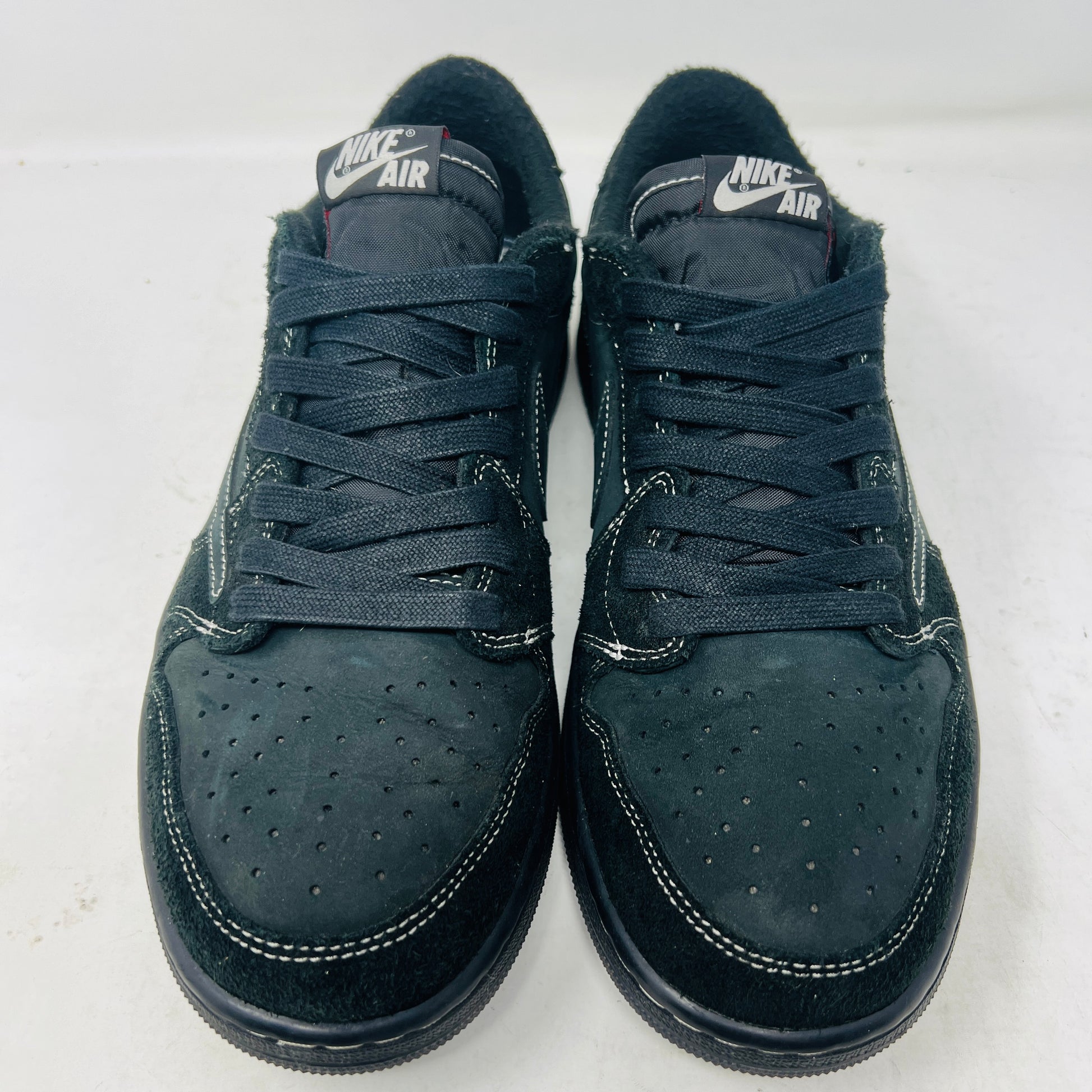 The Jordan 1 Retro Low OG SP Travis Scott Black Phantom sneaker in US size 11 features a clean upper with a visible swoosh. It includes two shoelace options: one red and one black-and-white patterned, sitting atop its box in pristine condition.