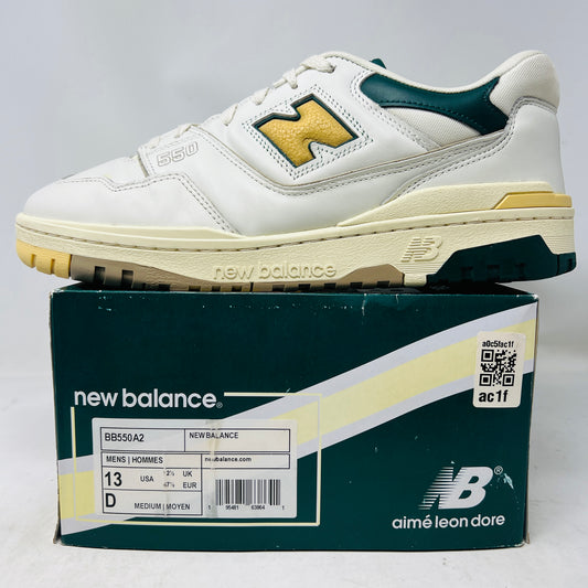 The New Balance 550 Aime Leon Dore Natural Green features a white sneaker with a yellow N logo on top of a green shoebox. The box is marked aime leon dore and mens size 13. These sneakers guarantee clean uppers and 100% authenticity for style and comfort seekers.