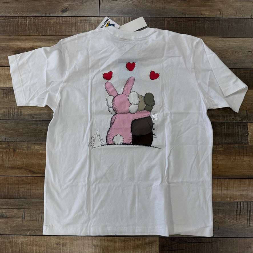 Brand new KAWS x Uniqlo Warhol UT Graphic 476350 T-shirt in white, featuring red lips design on the left chest; authentic with tags attached, shown on a wooden floor.