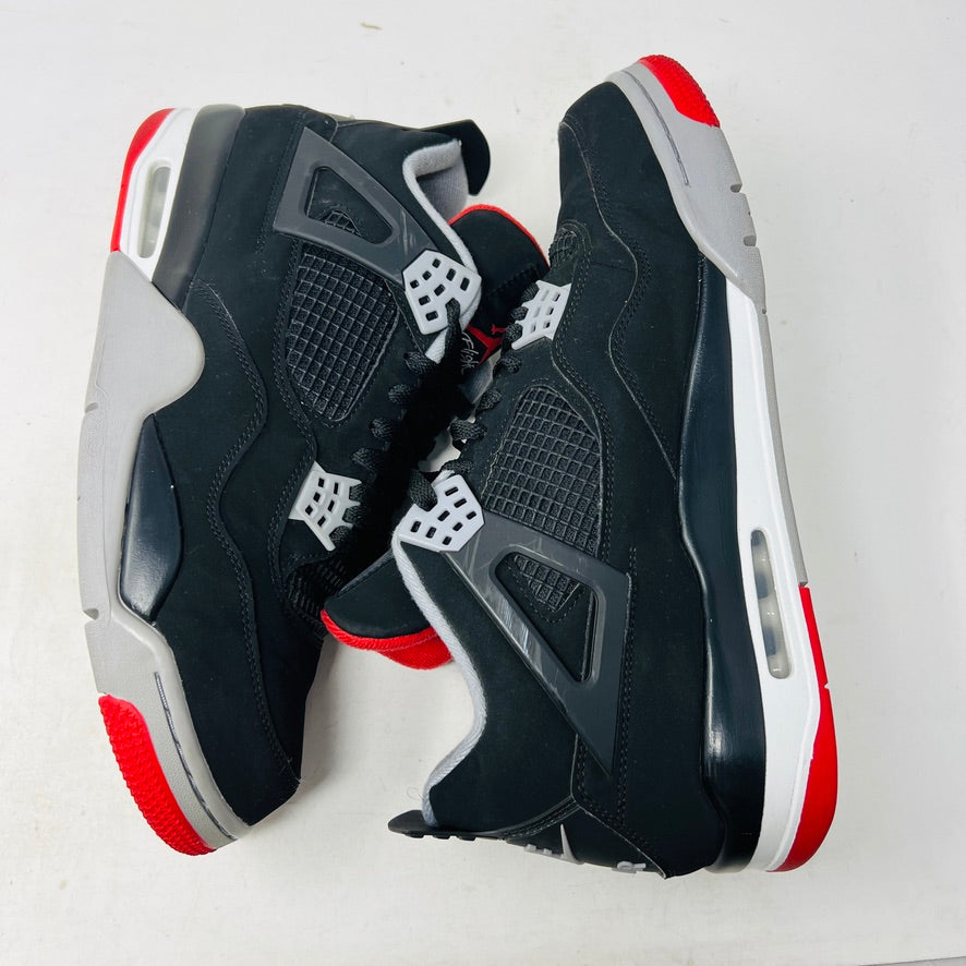 A pair of Jordan 4 Retro Bred (2019) sneakers with clean uppers are shown on a shoebox. These black and gray shoes have red accents, a visible Air unit, and rest on a speckled gray box featuring the red Jumpman logo. Available sizes include 12 and 13.5.