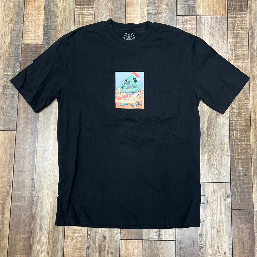 The preowned Palace Chrimbo Zoo T-shirt in black is showcased on a wooden floor, featuring a vibrant rectangular chest graphic. The artistic design boasts abstract shapes in multiple colors.