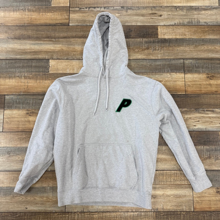 The Palace New Era LA Hood Grey Marl by Palace rests on a wooden floor. This stylish light gray hoodie features a drawstring hood, front pocket, and a subtle black P on the left chest, blending comfort with style.