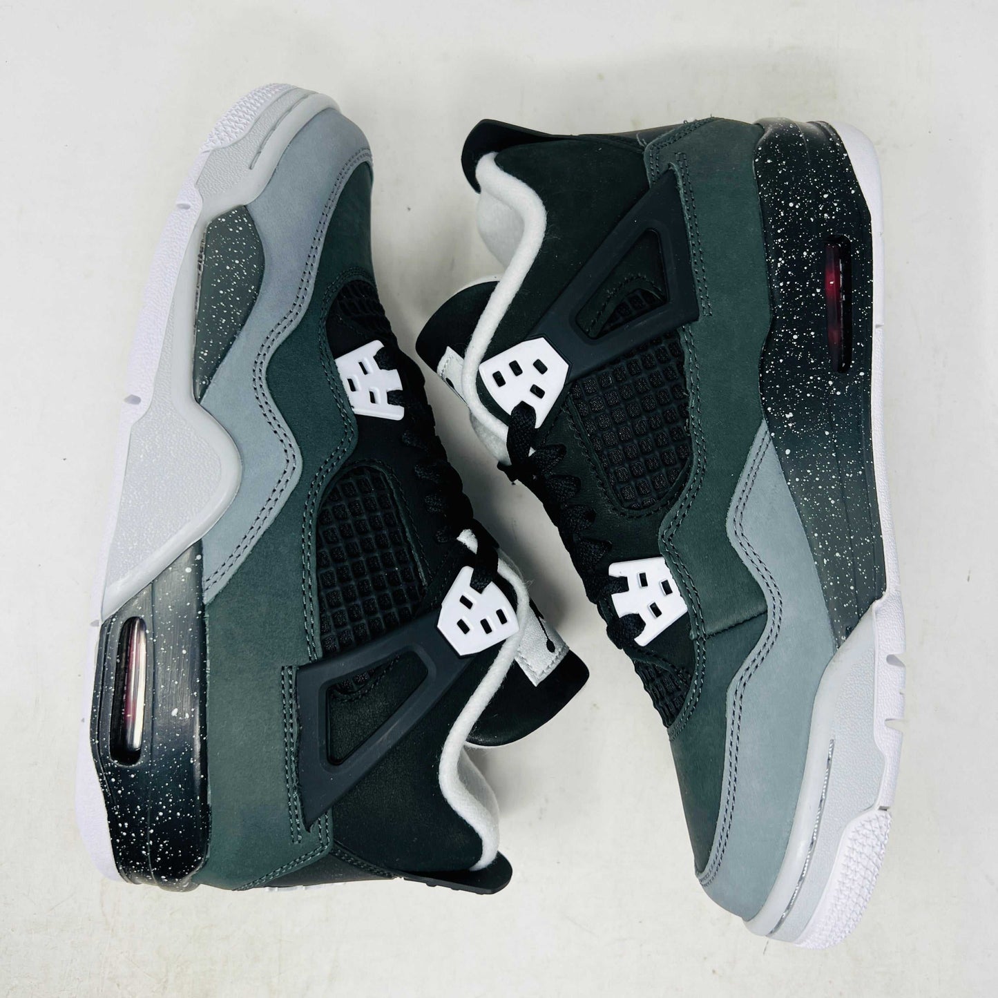 The Jordan 4 Retro Fear (2024) (GS) by Jordan is showcased on a matching shoebox. This BRAND NEW design features a gray and black athletic shoe with white accents, an authentic speckled midsole, mesh side panel, and distinctive lace pattern.