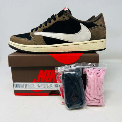 A brown and black Jordan 1 Retro Low OG SP Travis Scott Mocha with clean uppers and a large white swoosh sits on a Nike box. Two sets of extra laces in black and pink beside the box confirm their 100% authenticity. The shoe size is visible on the box label. Released in 2019.