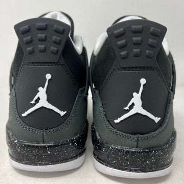 The Jordan 4 Retro Fear (2024) (GS) by Jordan is showcased on a matching shoebox. This BRAND NEW design features a gray and black athletic shoe with white accents, an authentic speckled midsole, mesh side panel, and distinctive lace pattern.