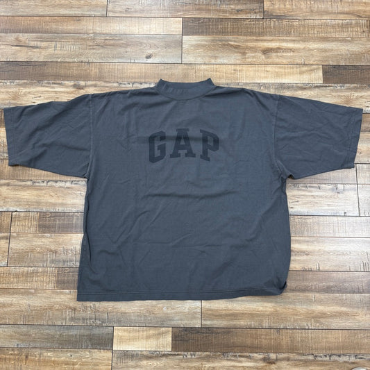 A brand new Yeezy Gap Dove 3/4 Sleeve Tee in gray features GAP in bold black letters on the front, laid flat on a wooden floor to highlight its 100% authentic style.