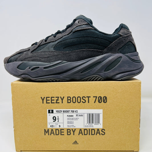 A dark gray Yeezy Boost 700 V2 Vanta sneaker, featuring clean uppers and slight heel drag, rests on its cardboard box displaying size info and labeled Yeezy Boost 700 V2 Made by Adidas.