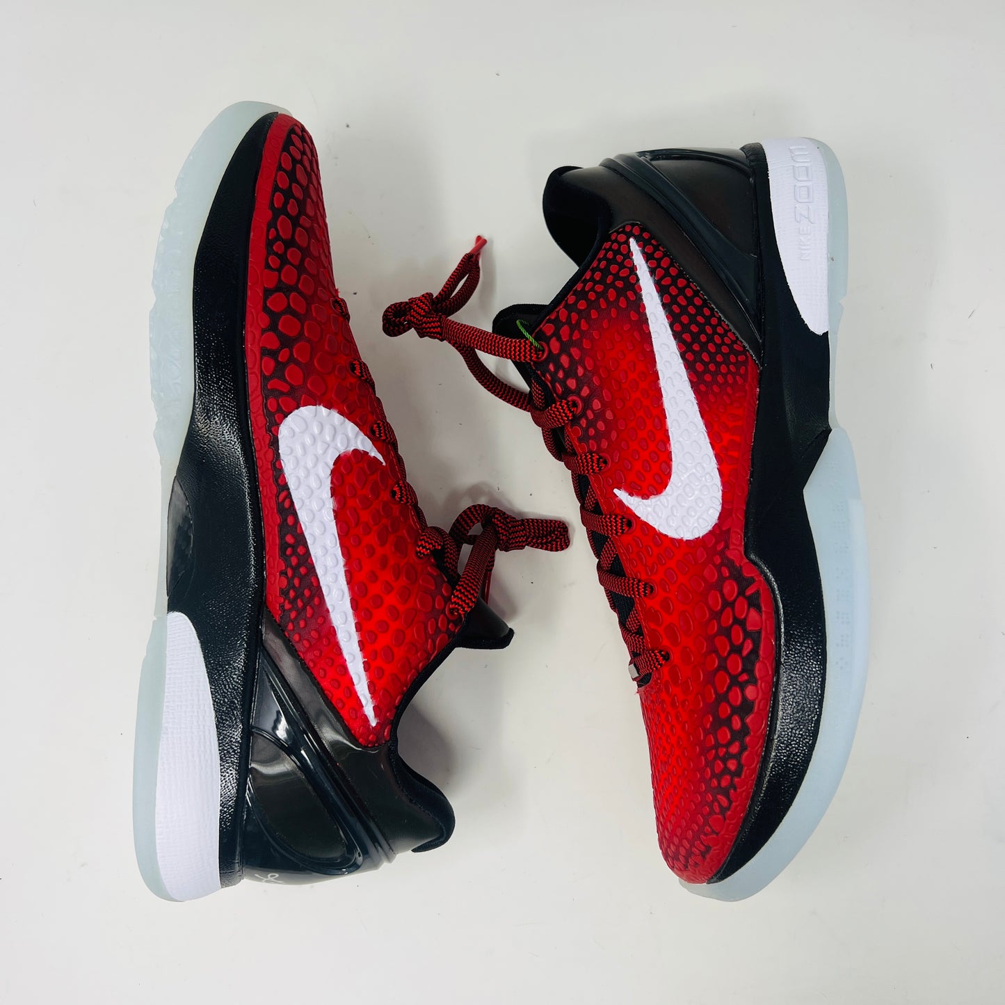 A brand new Kobe Nike Kobe 6 Protro Challenge Red All-Star (2021) sneaker, with a textured pattern and white swoosh, is showcased on a black shoebox. The authentic shoe has a black and white sole, red laces, and ZOOM on the side of the sole.