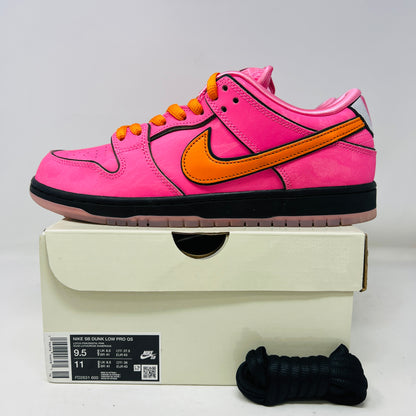 A vibrant pink Nike SB Dunk Low The Powerpuff Girls Blossom sneaker with an orange swoosh sits atop its box. It features clean uppers with black and pink details, orange laces, and comes 100% authentic, including an extra set of black laces beside the box.