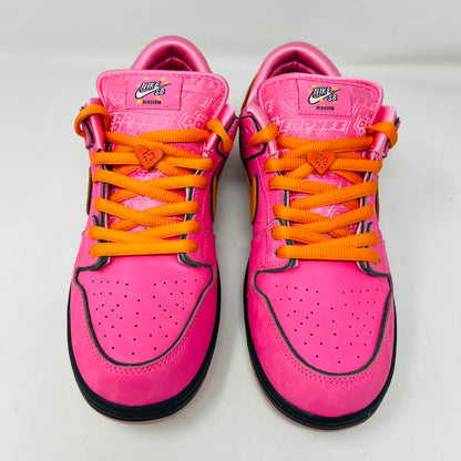 A vibrant pink Nike SB Dunk Low The Powerpuff Girls Blossom sneaker with an orange swoosh sits atop its box. It features clean uppers with black and pink details, orange laces, and comes 100% authentic, including an extra set of black laces beside the box.