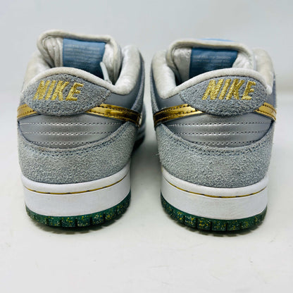 The Nike SB Dunk Low Sean Cliver, a gray and white sneaker with clean uppers and a gold swoosh, is displayed on its yellow-green box. It includes extra white and gold laces for style versatility. The size label reads 7.5, confirming authenticity and the perfect fit.