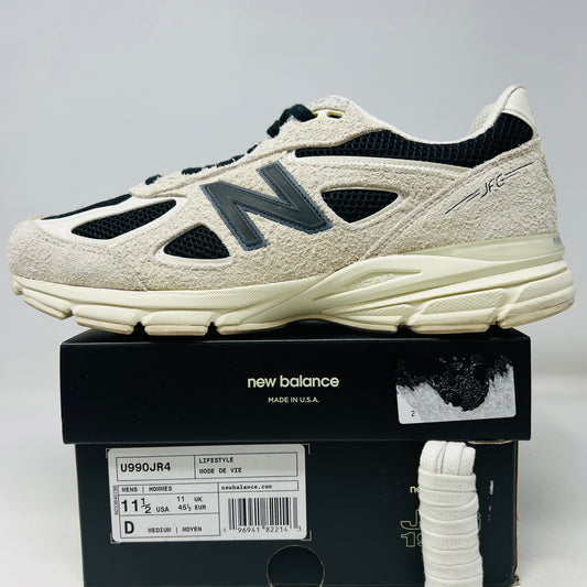 A New Balance 990v4 MiUSA Joe Freshgoods 1998 Intro sneaker, beige and black with white laces, sits on its box. Released in 2023, its angled to show side and top views, highlighting textured fabric and the iconic N logo.