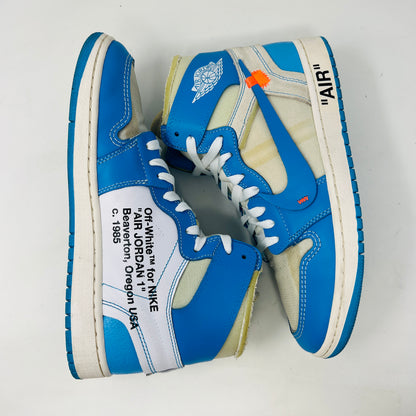 The Jordan 1 Retro High Off-White University Blue sneaker, by Jordan, in blue and white is displayed on a box with AIR text. It includes three extra laces (blue, white, orange), and a red authenticity tag against a pristine white background.