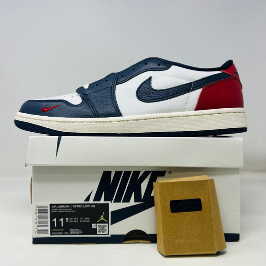 A Jordan 1 Retro Low OG Howard University sneaker, worn once, is showcased on its box. Featuring a navy, white, and red design with the iconic swoosh logo on the side, it includes a small brown card and extra laces nearby.