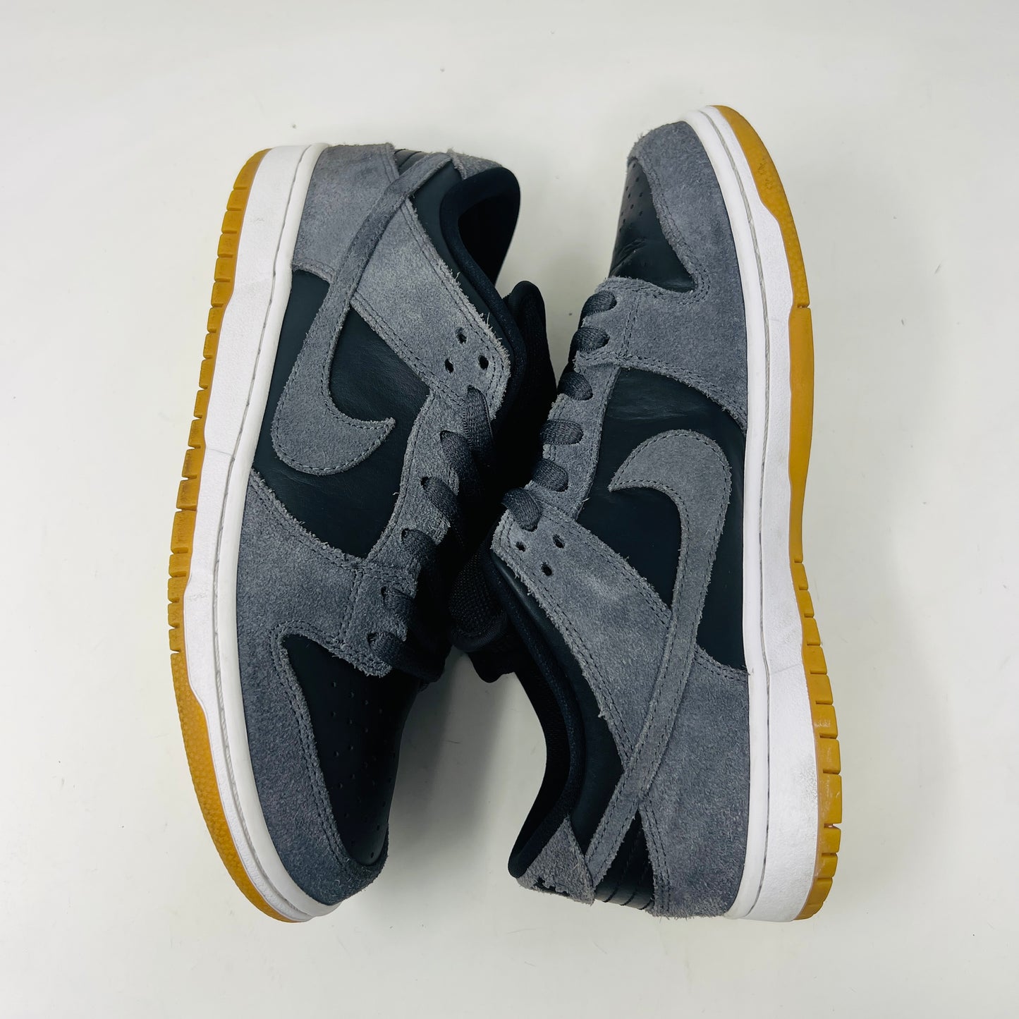 Displayed on a turquoise box, the 2018 Nike SB Dunk Low Dark Grey Black Gum shoe features gray suede uppers, a black Swoosh, and a gum sole. The slightly opened lid reveals product details inside.