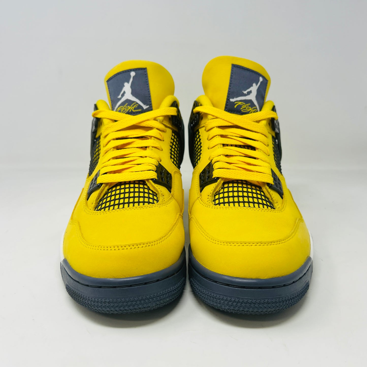 The Jordan 4 Retro Lightning (2021) in yellow, worn once and still pristine with its box, features black accents, a white midsole, and visible air cushioning. Sizes 10.5 and 12 are labeled alongside the Jumpman logo on both the sneaker and matching yellow box.