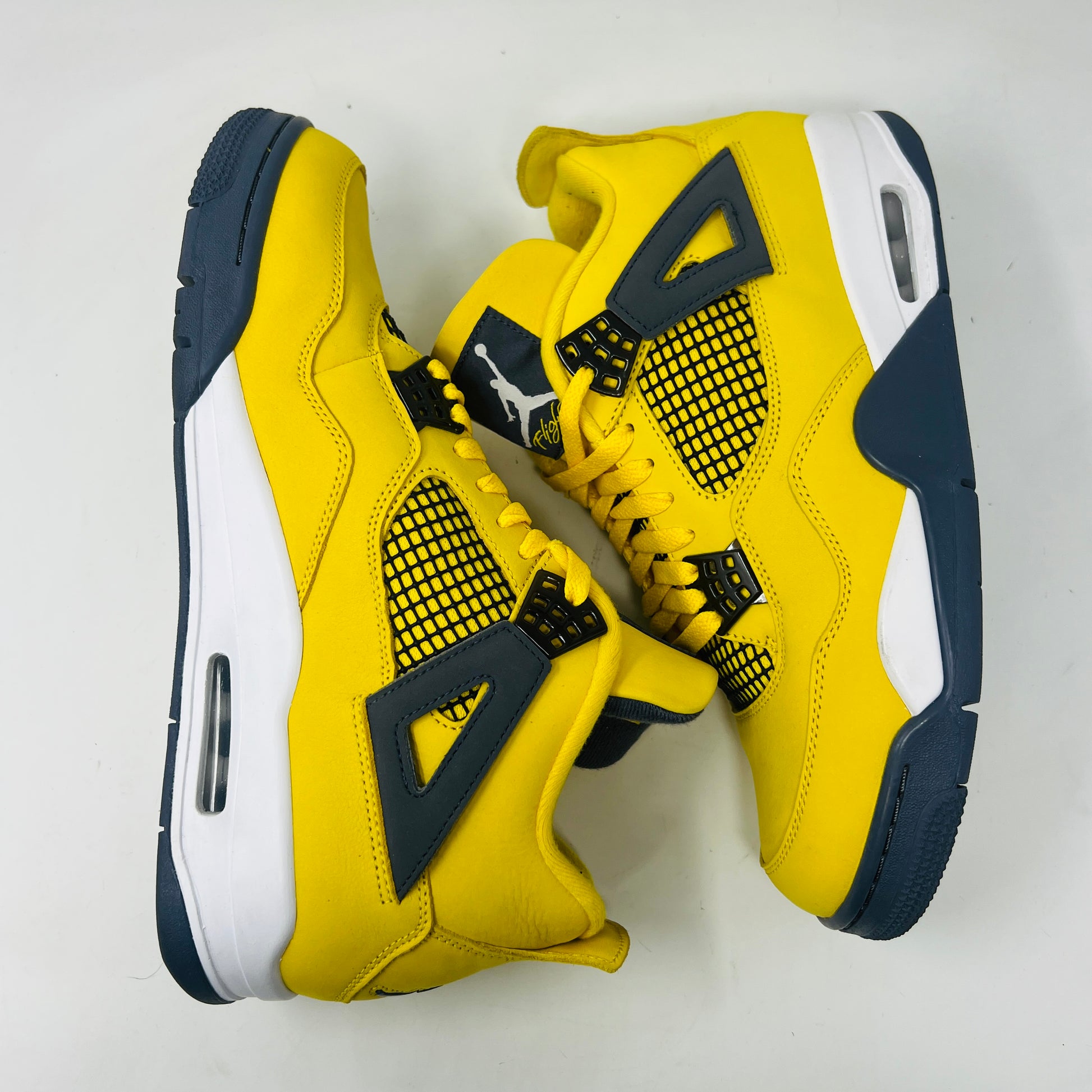 The Jordan 4 Retro Lightning (2021) in yellow, worn once and still pristine with its box, features black accents, a white midsole, and visible air cushioning. Sizes 10.5 and 12 are labeled alongside the Jumpman logo on both the sneaker and matching yellow box.