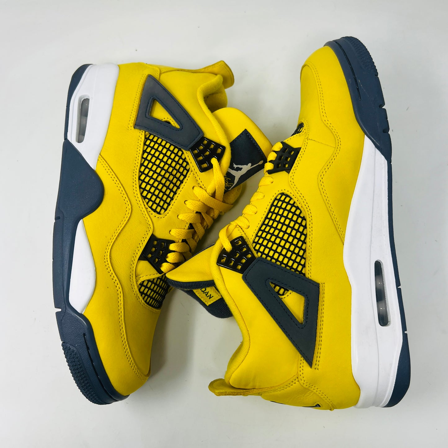 The Jordan 4 Retro Lightning (2021) in yellow, worn once and still pristine with its box, features black accents, a white midsole, and visible air cushioning. Sizes 10.5 and 12 are labeled alongside the Jumpman logo on both the sneaker and matching yellow box.