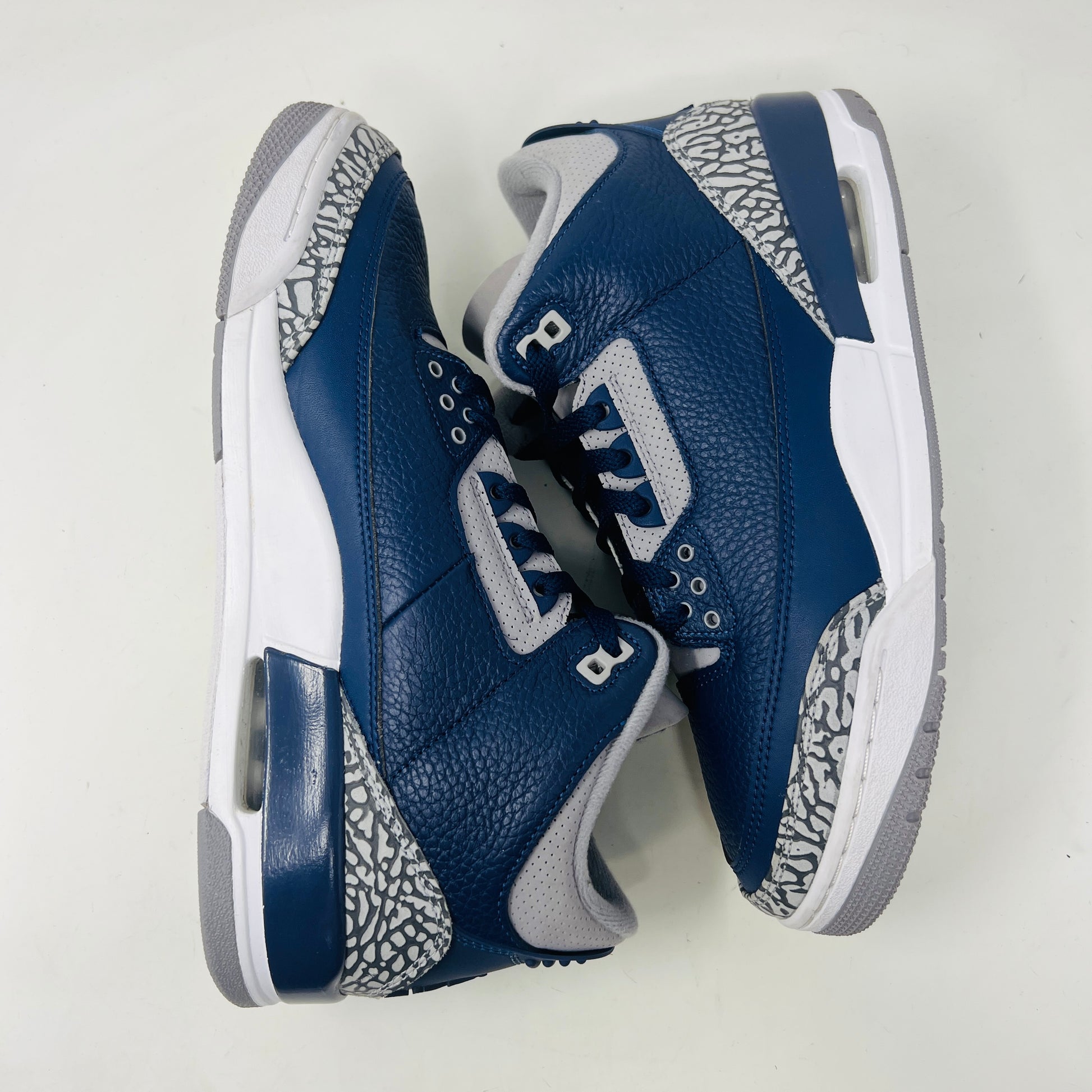 A size 10 Jordan 3 Retro Georgetown (2021) sneaker, in blue and gray with elephant print accents and a white midsole, worn once on its patterned box. The box has minor DMG but matches the sneakers stylish appeal.