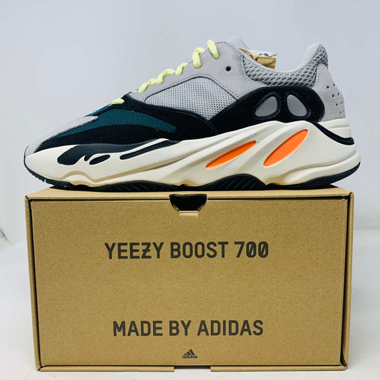 A Yeezy 700 Waverunner with a multicolor scheme of gray, black, teal, and orange rests on a Yeezy Boost 700 Made by Adidas box. Sales are final on these authentic shoes.