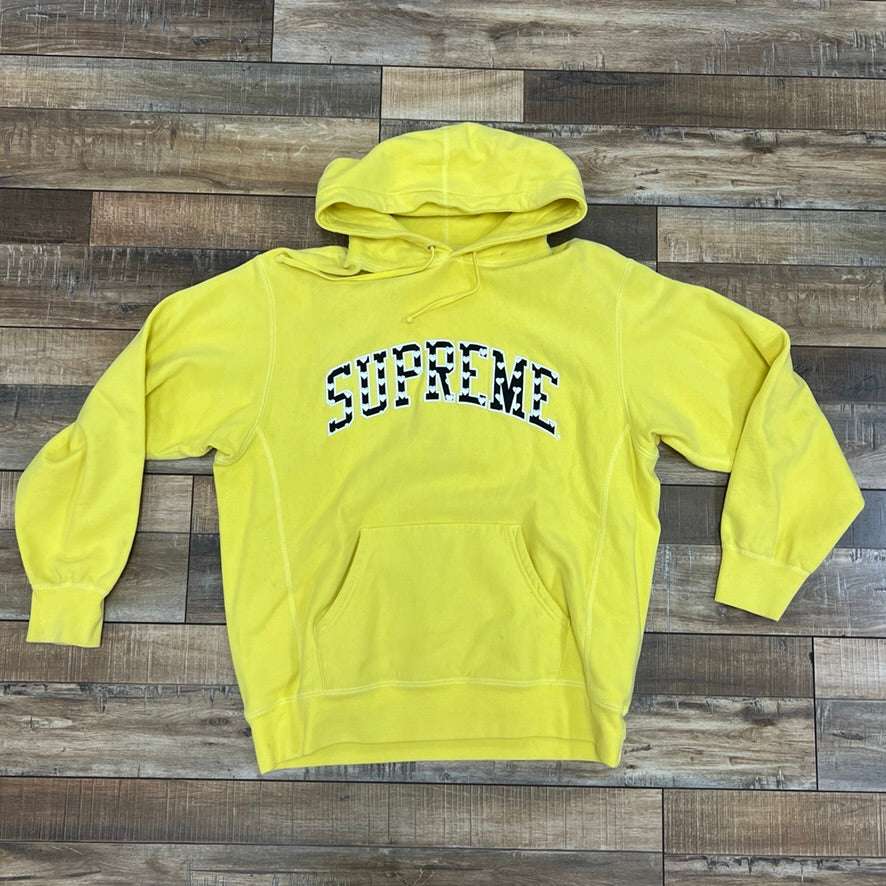 Supreme Hearts Arc Hoodie Yellow on wooden floor.