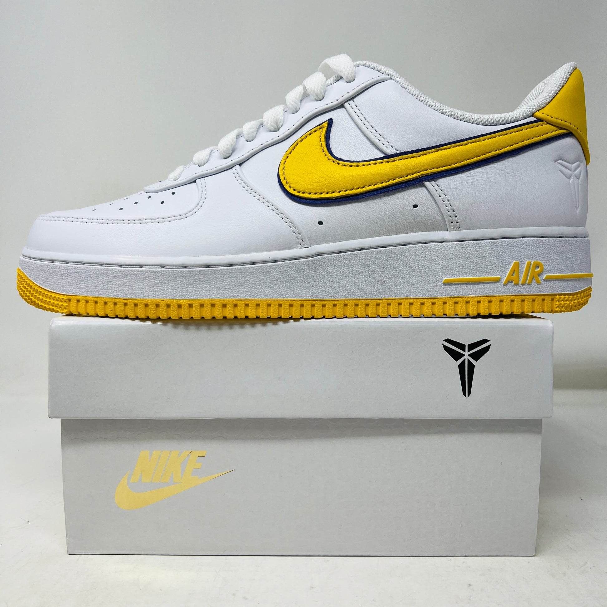 Nike Air Force 1 Low Retro QS Kobe Bryant Lakers Home sneaker displayed on box with yellow and white accents, brand new condition.