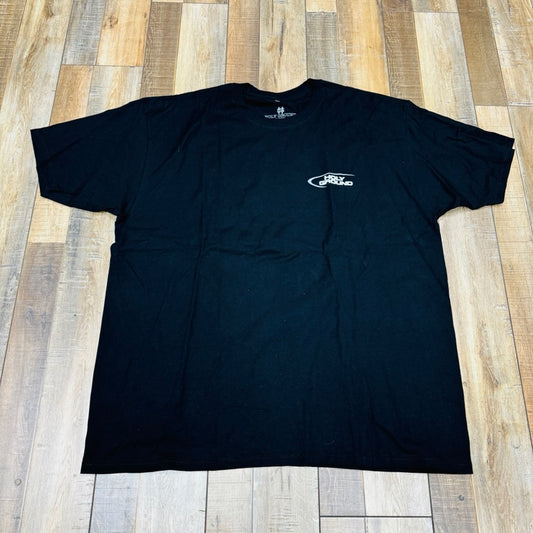 Holy Ground HG And-1 Tee in black, featuring a small white chest logo, is laid flat on a wooden floor.