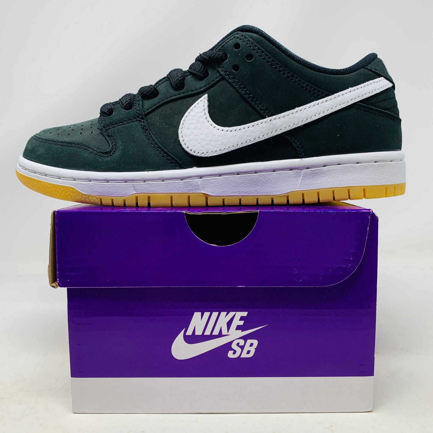 Nike SB Dunk Low Pro Black Gum sneakers, brand new, on a purple Nike SB box.