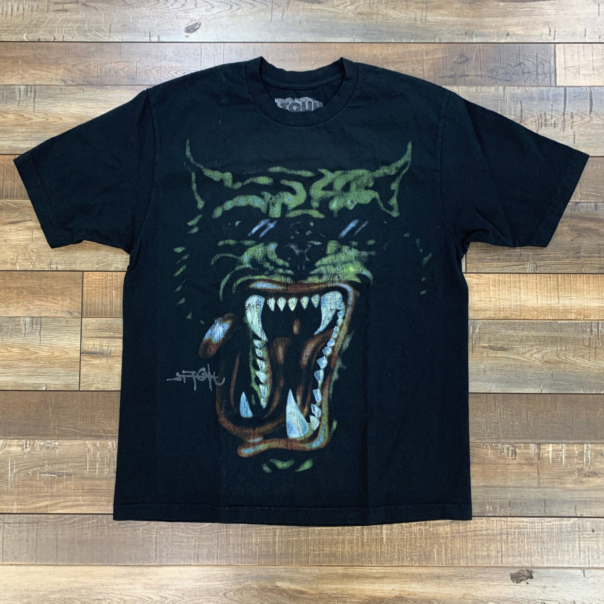 Travis Scott Utopia Tour Tee Black with graphic print design on wooden background.