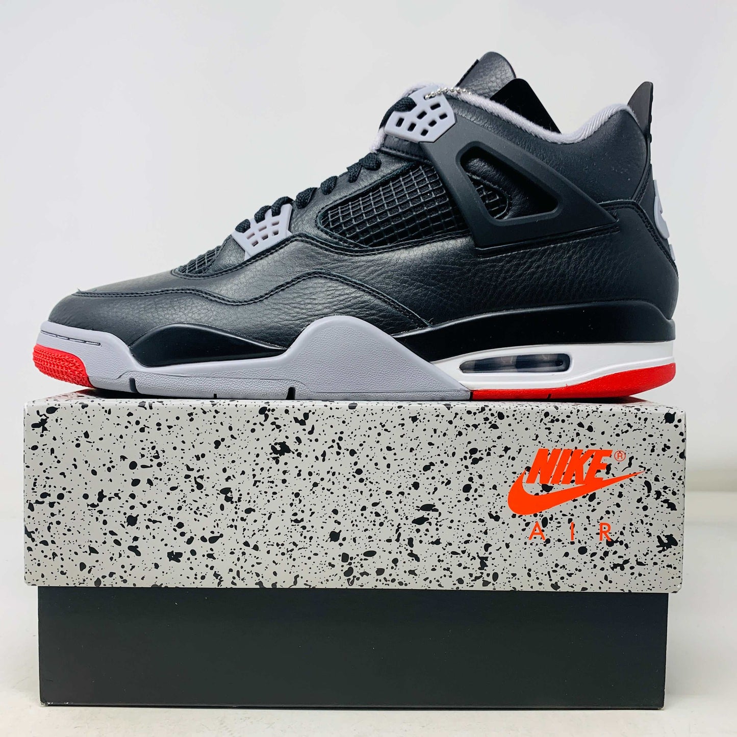 Jordan 4 Retro Bred Reimagined sneaker with black and red colorway, leather and mesh upper, Jumpman logo on tongue, Nike Air branding on heel, Air-Sole midsole.