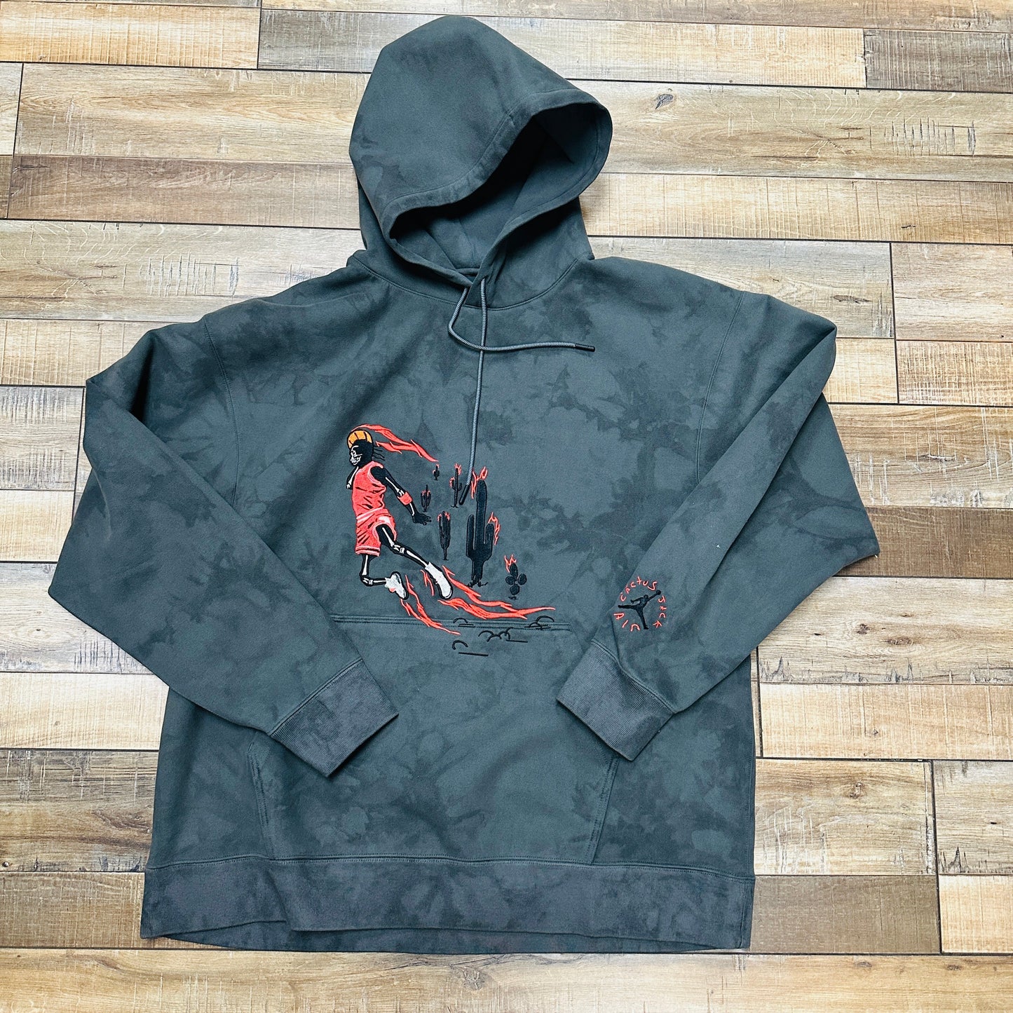 Travis Scott Jordan Washed Suede Hoodie Grey, brand new condition on wooden floor background.