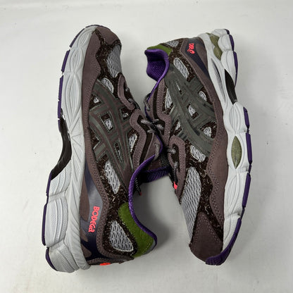 The ASICS Gel-NYC Bodega After-Hours sneakers, in brown with gray, purple, and green accents, sit on a box. A packet of extra red laces is attached. The size and details are prominently shown on the label.