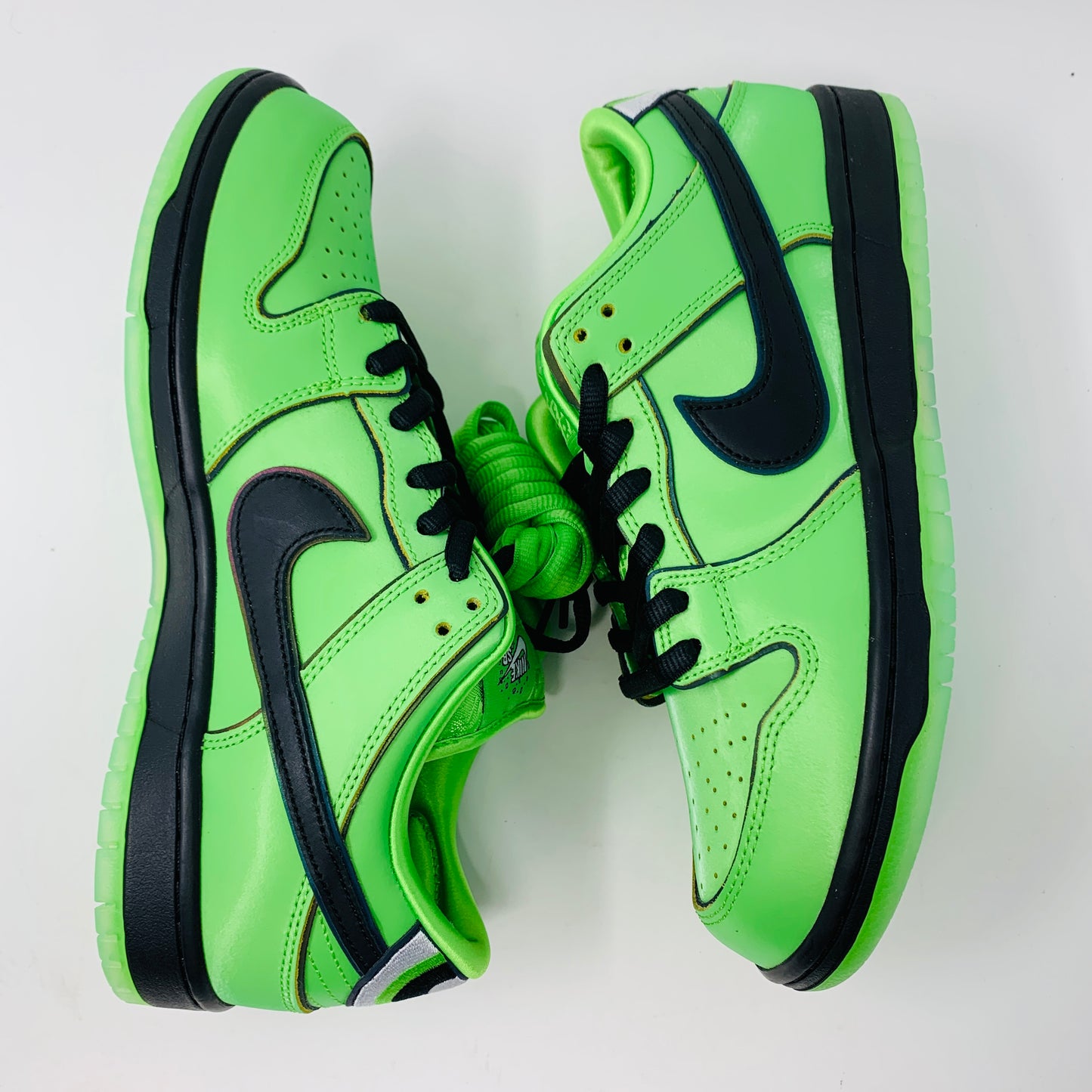 The Nike SB Dunk Low The Powerpuff Girls Buttercup sneakers feature a vibrant green design with black accents, including laces and the iconic swoosh, displayed on a plain white background.