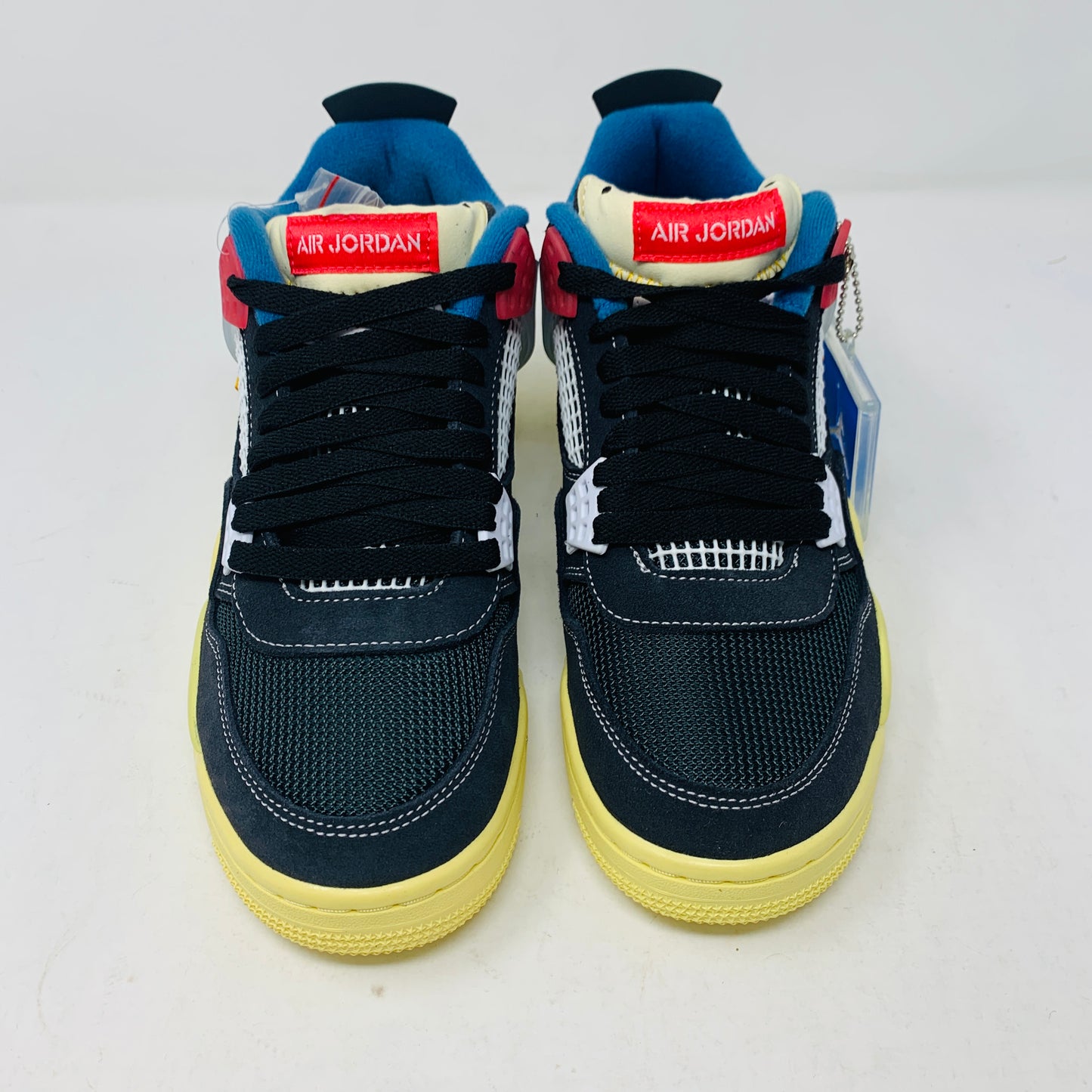 The Jordan 4 Union Noir sneaker in black, yellow, blue, and red is 100% authentic and brand new. It features a visible air unit in the heel, a translucent tab with the Jumpman logo, a matching shoebox, and extra laces for versatility.