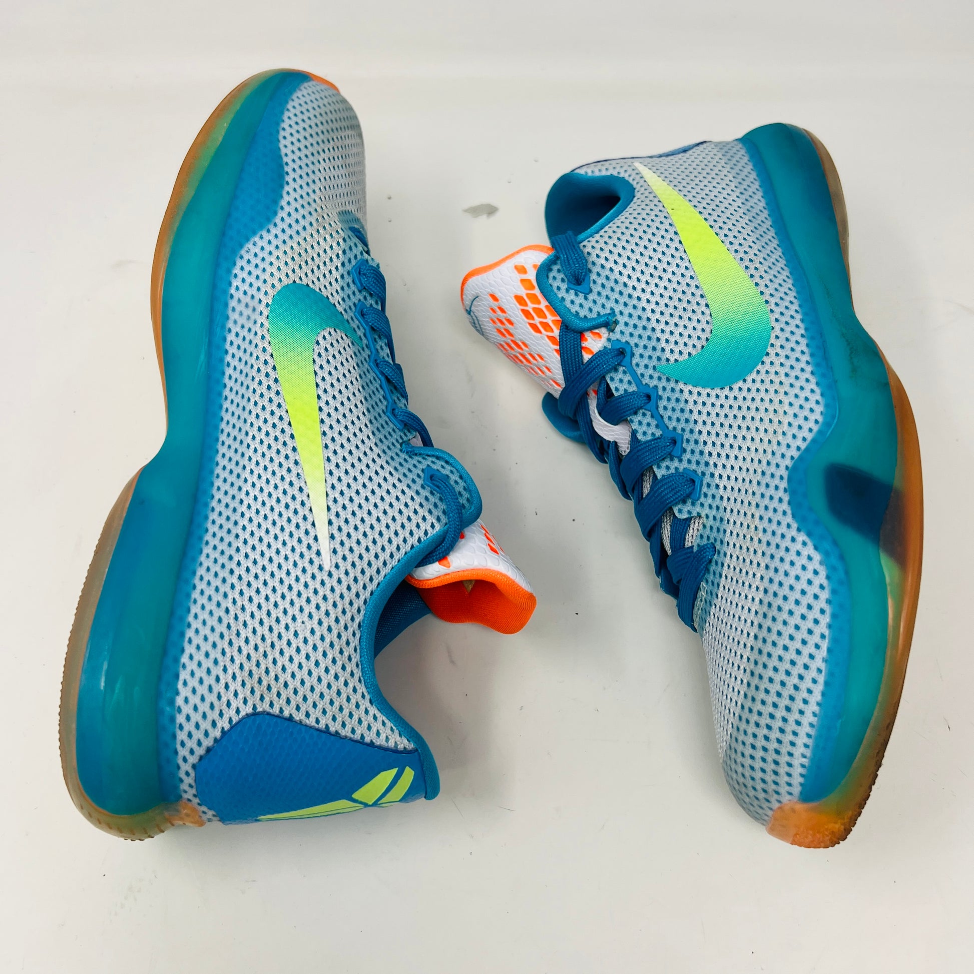 The Kobe 10 GS High Dive from Nike, in size 7Y, is on display with a blue upper, gradient yellow-green Swoosh, orange lining, and a multicolored sole. Its resting on its black box and shows normal wear.