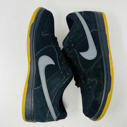 A pair of authentic Nike SB Dunk Low Fog sneakers in black with gray swoosh logos and vibrant yellow soles, accompanied by extra laces, displayed on a pristine white background from Holy Ground Sneaker Shop.