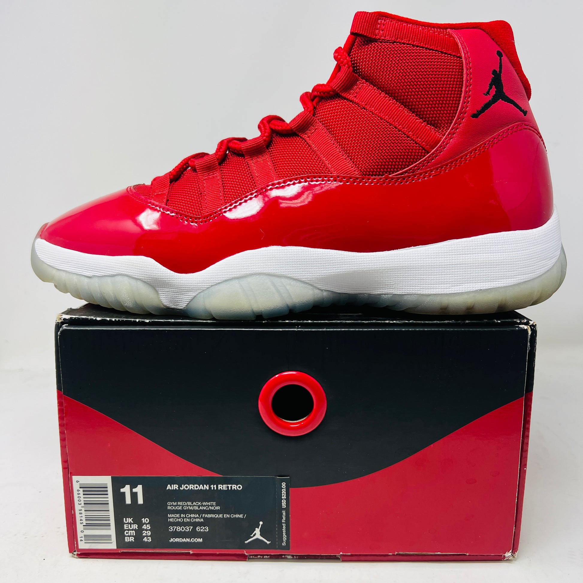 The Jordan 11 Retro Win Like 96 sneaker, featuring red glossy patent leather and sleek uppers, rests on its matching black/red box from 2017. Perfect for general wear, it boasts the iconic Jumpman logo, and the box highlights size and product details.