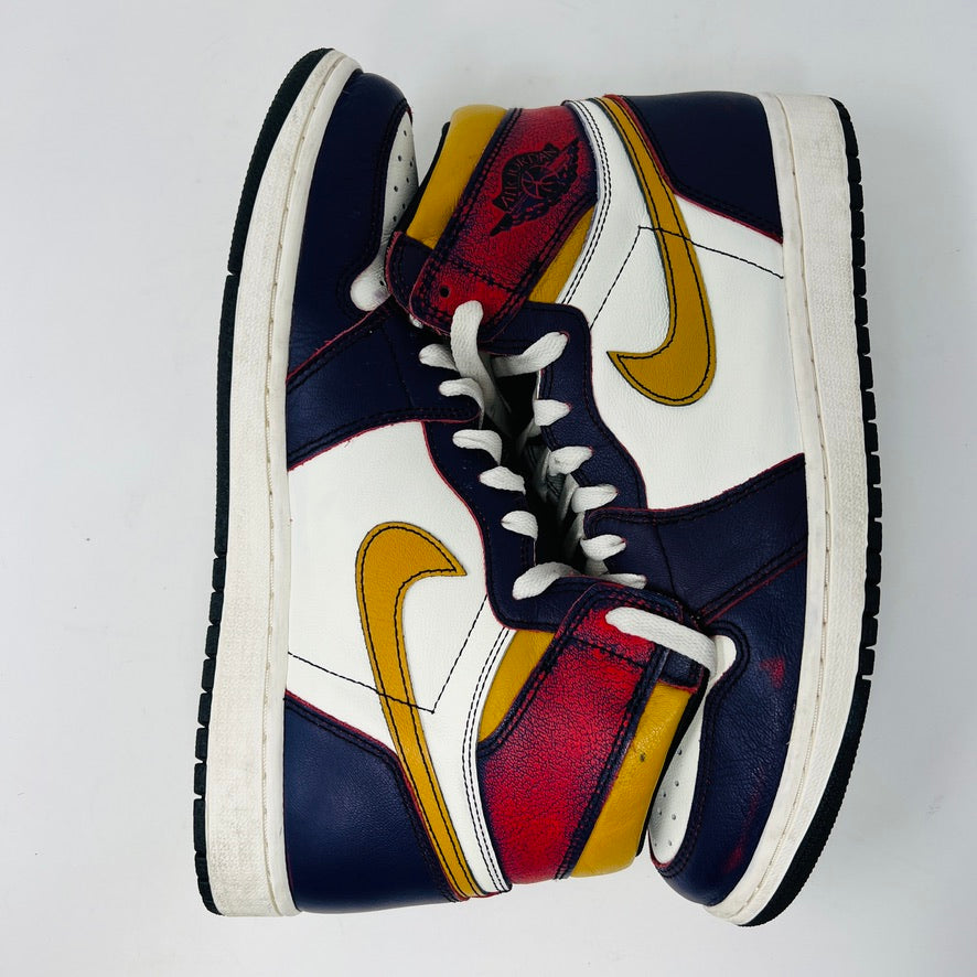 The Jordan 1 Retro High OG Defiant SB LA to Chicago sneakers feature a vibrant design with navy blue, white, red, and yellow panels. Each shoe showcases a yellow swoosh logo on the side. The sneakers have white laces and black soles with a white midsole.