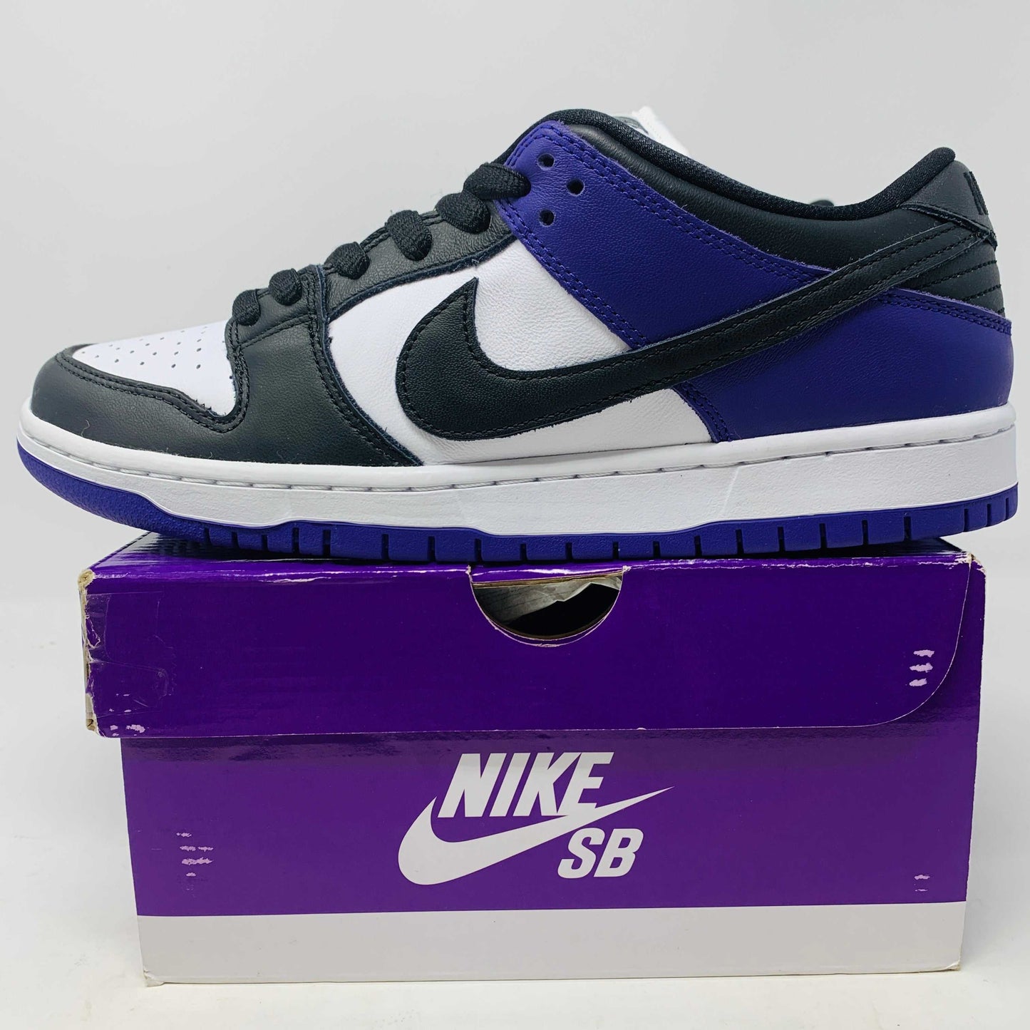 Nike SB Dunk Low Court Purple sneakers with vibrant purple highlights and iconic swoosh, displayed on a matching box.