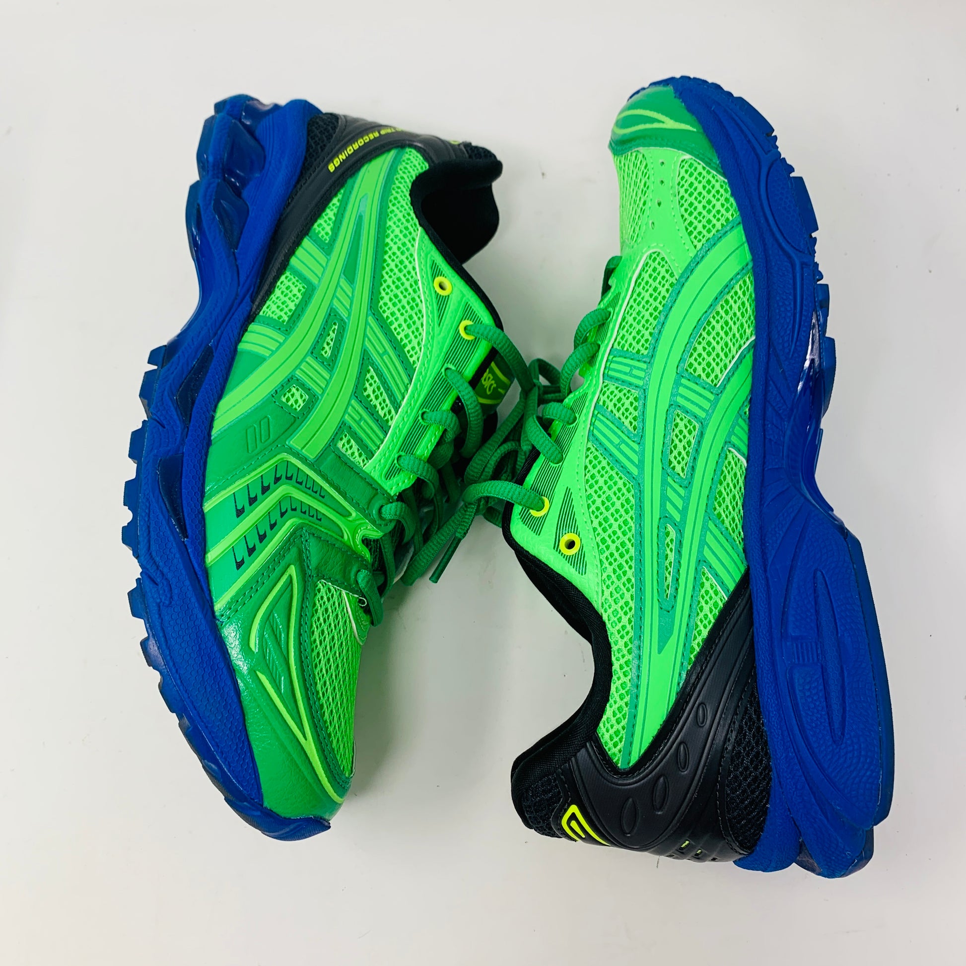 The ASICS Gel-Kayano 14 Field Trip Recordings Fern Green athletic shoes feature a vibrant mix of green and blue with intricate patterns, mesh detailing, and striking black accents. They are displayed side by side on a plain white background.