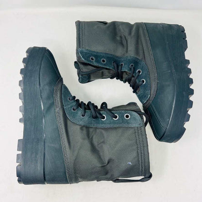 A 2015 Adidas Yeezy 950 Pirate Black boot is displayed on its box against a plain white background. This authentic Yeezy features a high lace-up design and sturdy ridged soles. The box includes size details, a partially visible label, and extra laces for added versatility.