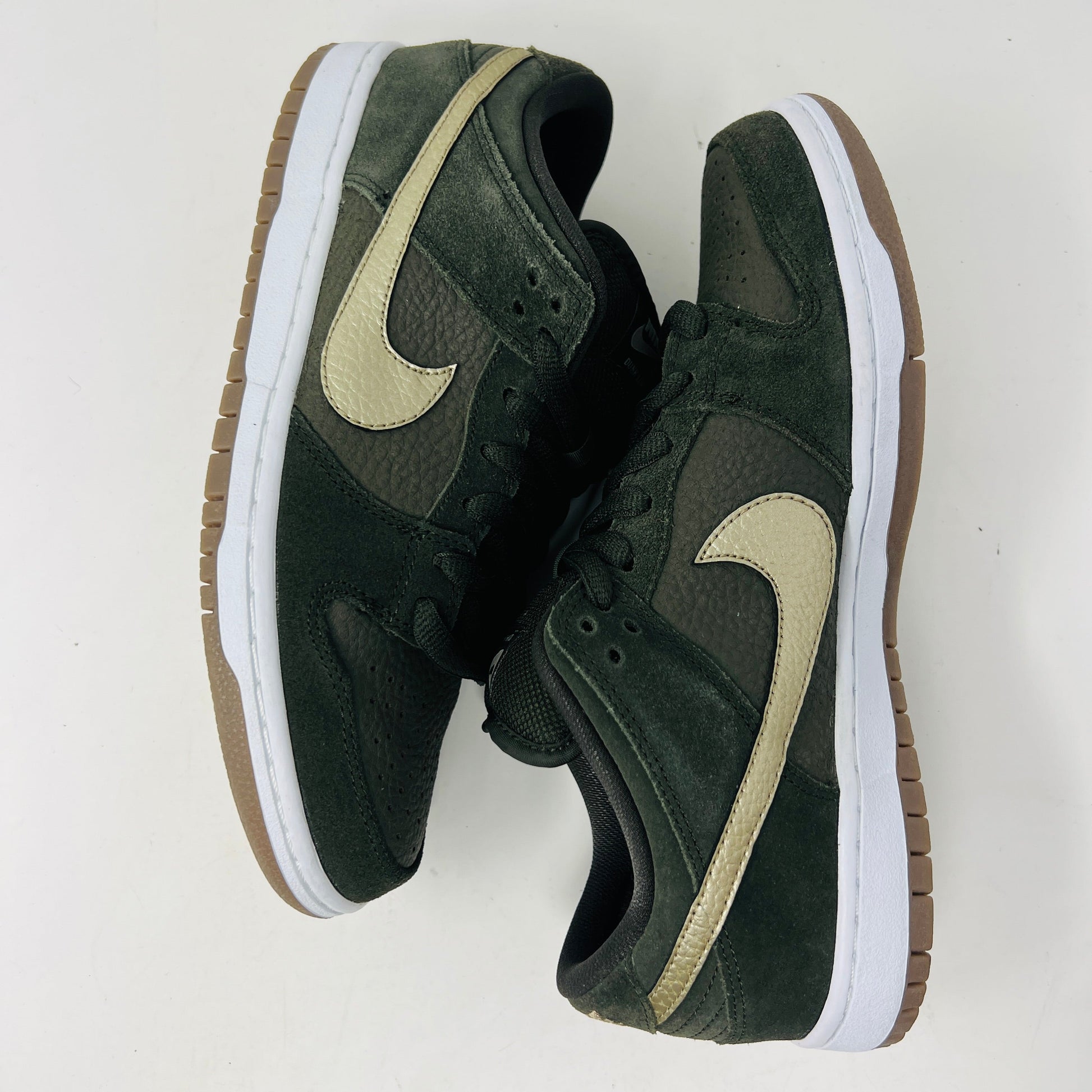 A pair of Nike SB Dunk Low Sequoia White Gum shoes with a green and brown design, white sole, and beige swoosh logo sit on a white surface, guaranteed 100% authentic.