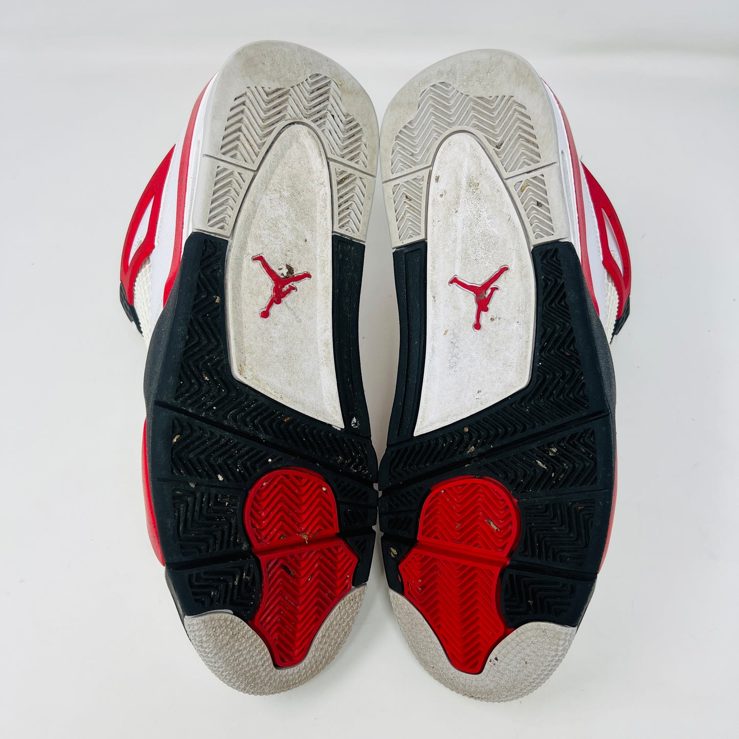 The Jordan 4 Retro Red Cement sneakers, by Jordan, are showcased on their box. They feature authentic white leather, clean uppers with red accents, black netting, and visible air cushioning. The textured box includes a size label.