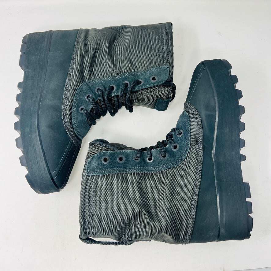 A 2015 Adidas Yeezy 950 Pirate Black boot is displayed on its box against a plain white background. This authentic Yeezy features a high lace-up design and sturdy ridged soles. The box includes size details, a partially visible label, and extra laces for added versatility.