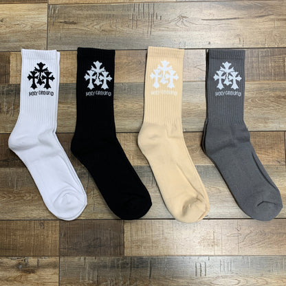 Holy Ground Socks in white, black, beige, and gray displayed on wooden floor.