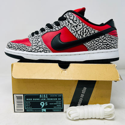 A genuine Nike SB Dunk Low Supreme Red Cement (2012) sneaker, featuring red and black elephant print details, rests on a cardboard box and comes with extra white laces for added style versatility.