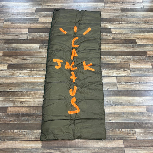 Travis Scott Cactus Jack Sleeping Bag Olive with logo on wooden floor.